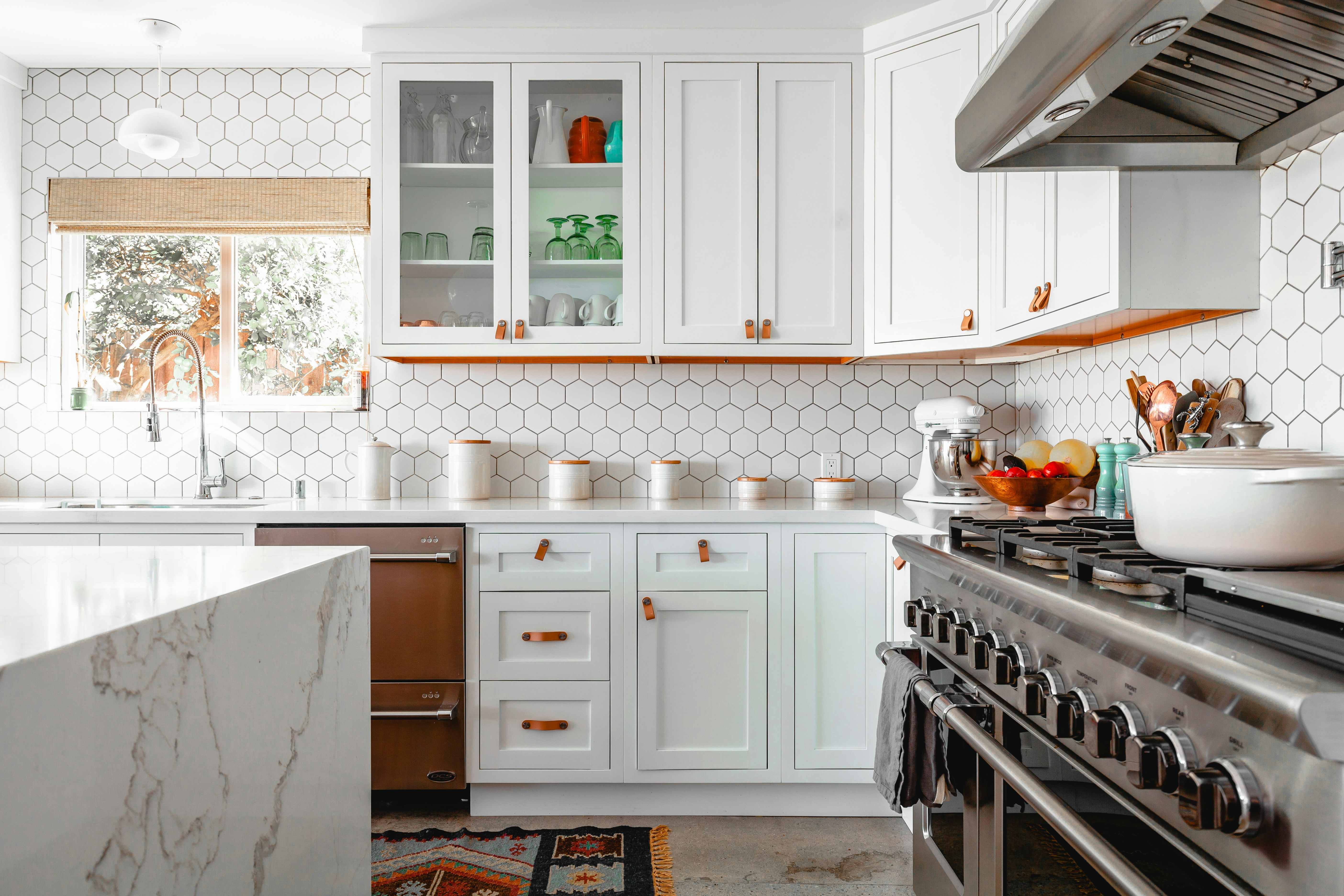Modern kitchen renovation with custom cabinetry, marble countertops, and hexagonal tile backsplash